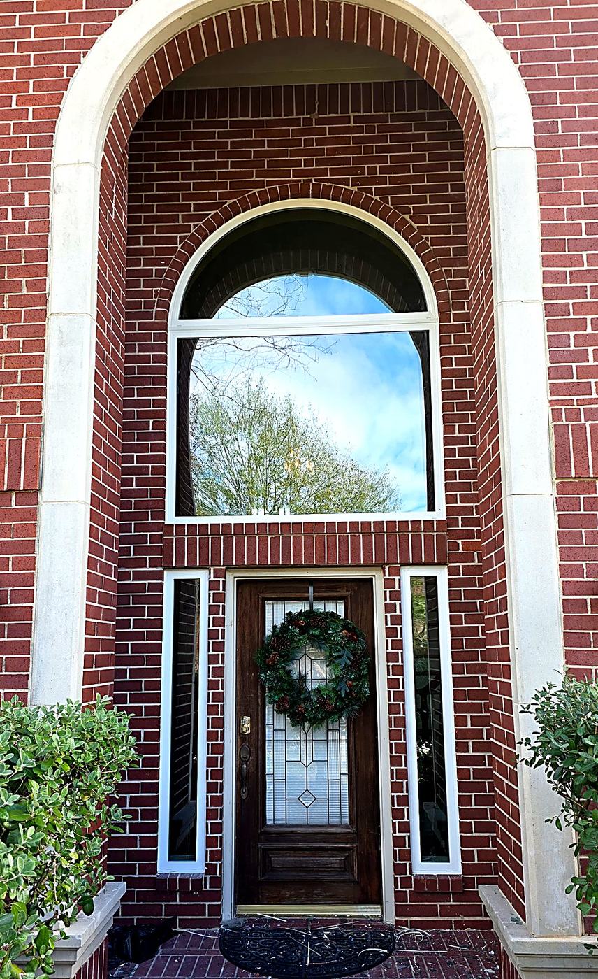 Arched transom window above a brick home entryway